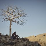 Kumbanu, 51, takes rest while travelling across a dry and arid landscape to reach Namibia.