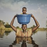 'We make sacrifices to bring our children to safety using bucket' Nyalong Wal, 36, carries her daughter, Nyamal Tuoch, 2, to dry land