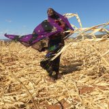 Loko and her baby at their destroyed maize field. Their crops are continuously failing due to climate change