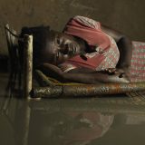 "The dikes usually break at night, so when it broke that night I couldn't do anything because it was dark and my children and I were alone at home so we just went back to sleep. We slept on the top of the bed even while the water came inside the house." Nyapini Yiel, 23, lyes in her bed surrounded by flood water.
